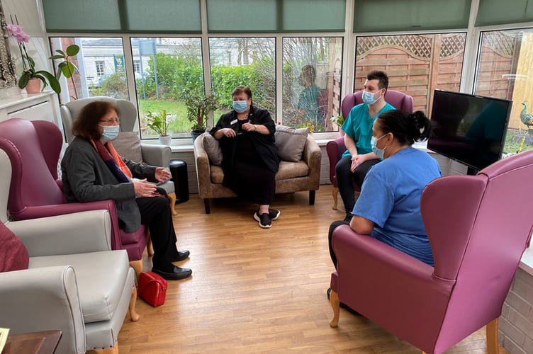 A group of people and medicl staff sitting down, chatting.