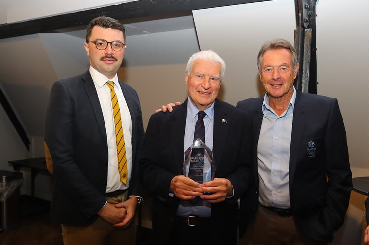 Abergavenny Hockey club president Trevor Scott, centre, and club chairman Luke Rees, left with the commemorative glass presented in honour of Bill Griffiths by Olympic gold medallist Lynn Davies, right 