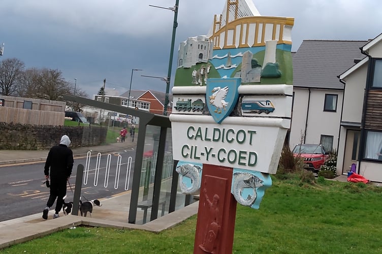 A welcome sign in Caldicot denoting its proximity to the Severn Bridge which is depicted along with the castle and railway line. 