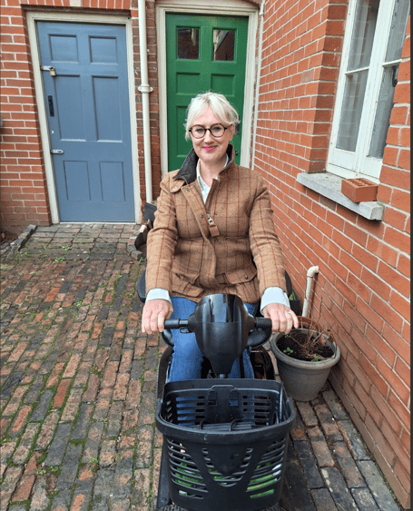 Suzy Mills scootering from Bridges Community Centre to deliver a flood damaged replacement mobility aid to temporary accommodation in Wyesham.