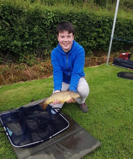 A smiling junior angler with a common Carp that was caught & safely released to grow bigger.