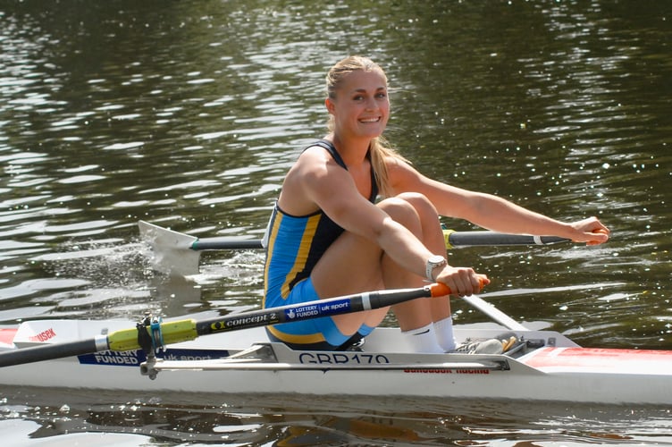 A sculler heads for the start with a sunny smile